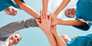 five people putting their hands together in a huddle